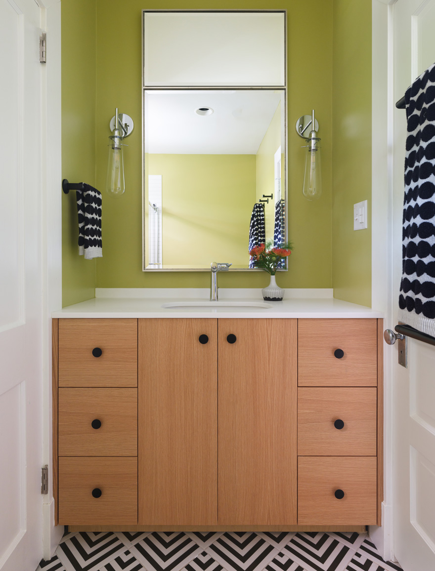 Powder room with green walls, wood vanity, and geometric tile floor in Webster Groves, Missouri — architect remodeling St. Louis